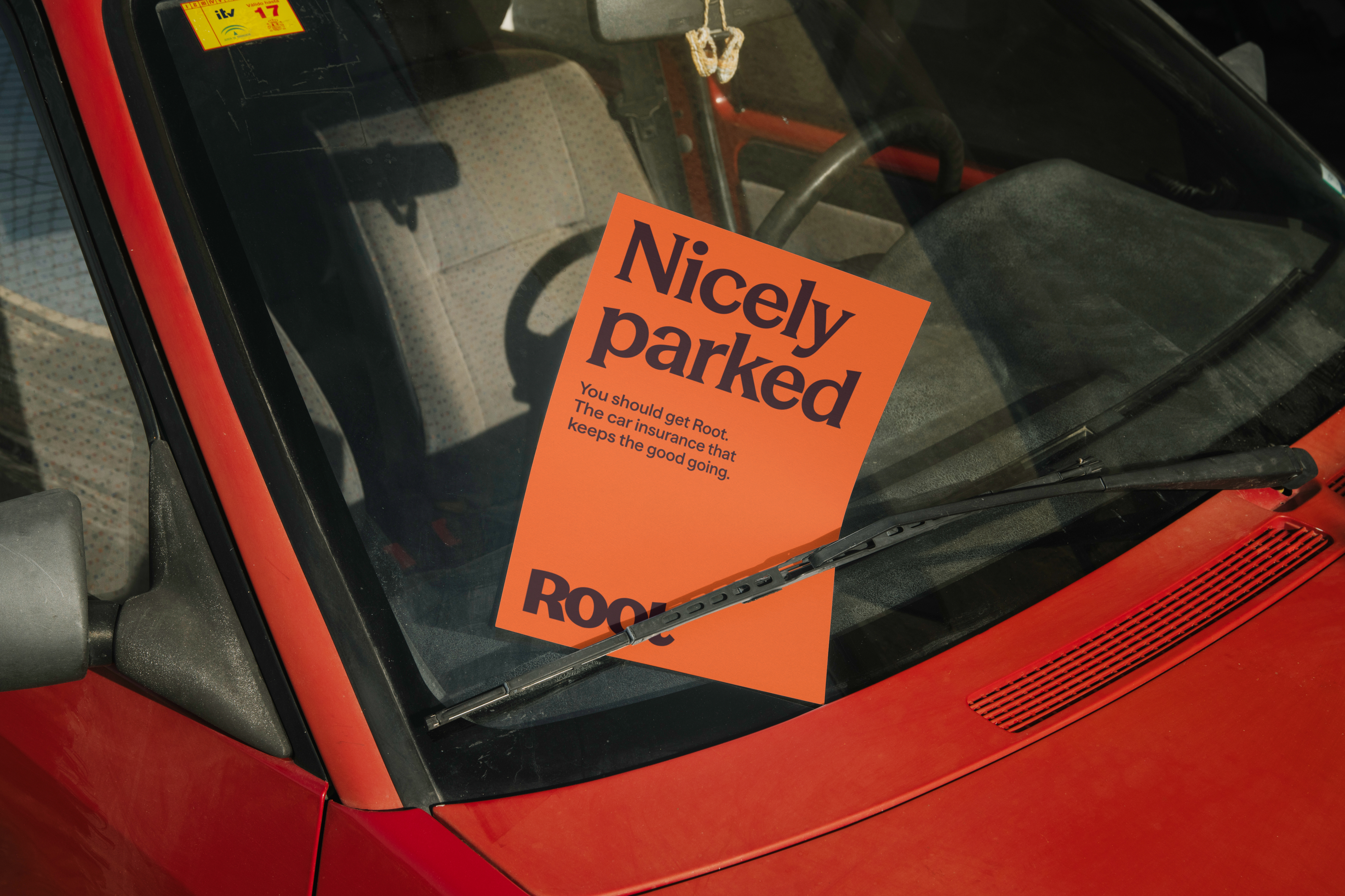 An orange Root flyer reading Nicely parked beneath the windshield wiper of a red car
