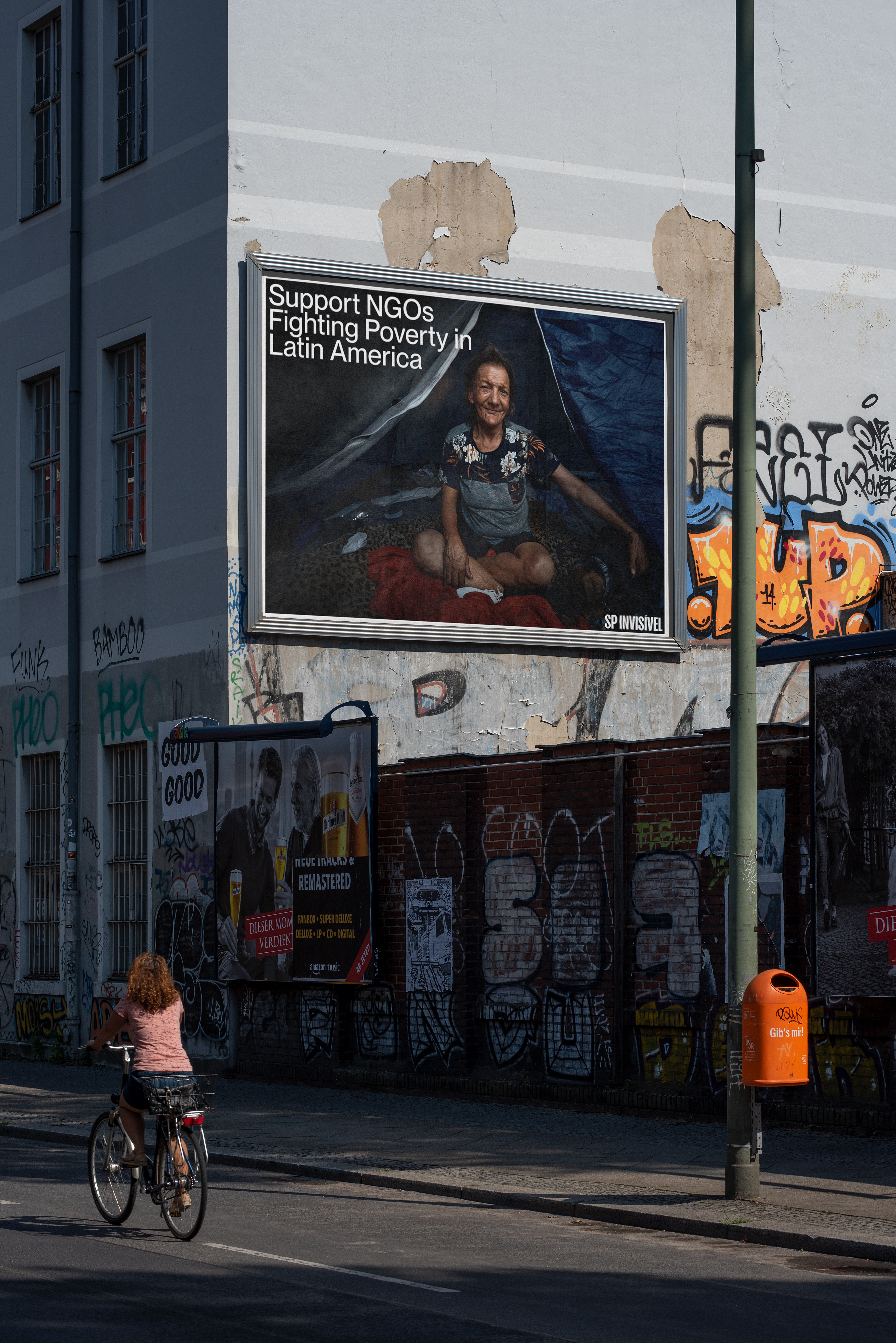 SP Invisível campaign billboard on an urban wall, encouraging support for NGOs fighting poverty in Latin America.