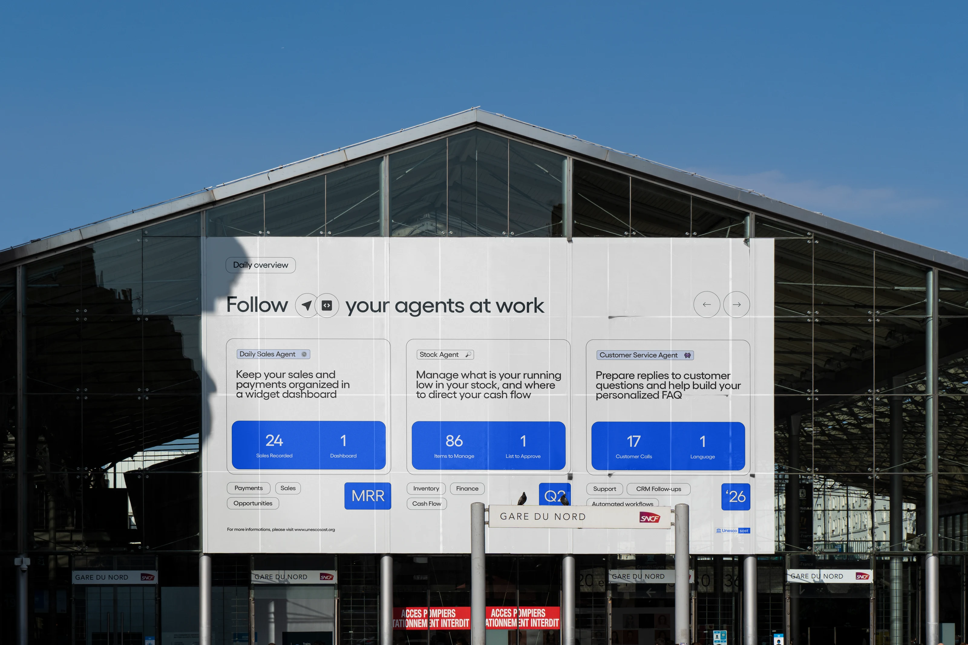 UNESCO project billboard at Gare du Nord showing Daily Sales, Stock, and Customer Service agents under Follow your agents at work